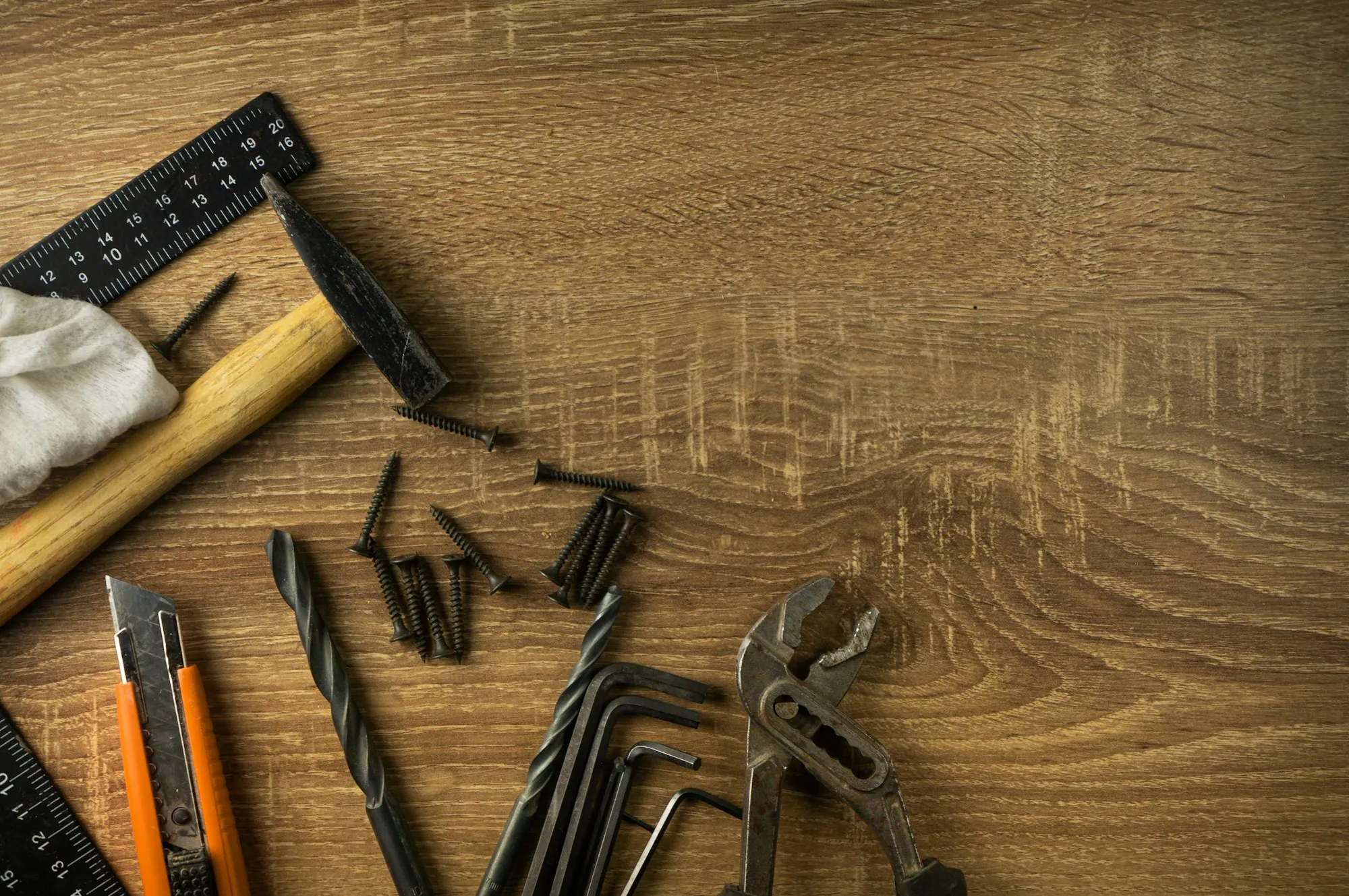 Pliers, drill bits and hand tools on a wood table