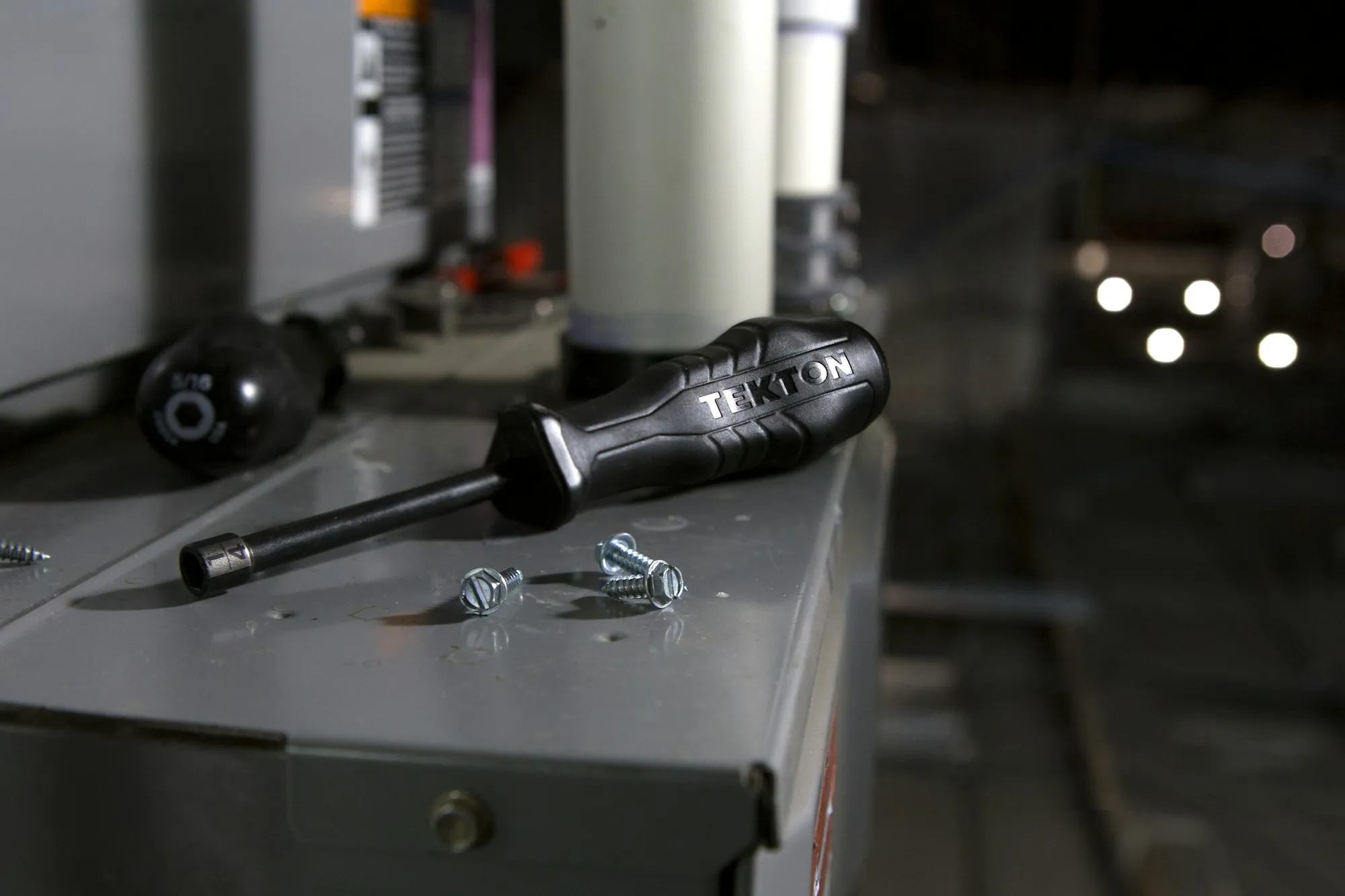 Screwdriver and screws resting on a metal panel